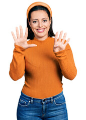 Young hispanic girl wearing casual white t shirt showing and pointing up with fingers number nine while smiling confident and happy.