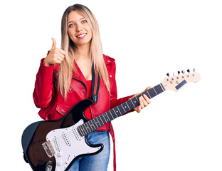 Fototapeta premium Young beautiful blonde woman playing electric guitar smiling happy and positive, thumb up doing excellent and approval sign