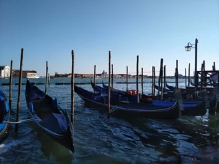 Foto op Plexiglas Stad aan het water Row of gondolas moored on the pier of the water in Venice, Italy