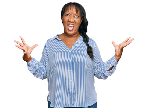 Hispanic middle age woman wearing casual clothes crazy and mad shouting and yelling with aggressive expression and arms raised. frustration concept.