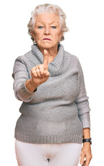 Senior grey-haired woman wearing casual winter sweater pointing with finger up and angry...