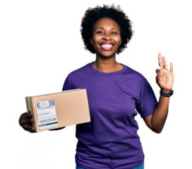 African american woman with afro hair holding delivery package doing ok sign with fingers, smiling friendly gesturing excellent symbol