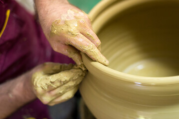 Man professional potter making pottery from wet clay in his pottery workshop