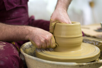 Man professional potter making pottery from wet clay in his pottery workshop