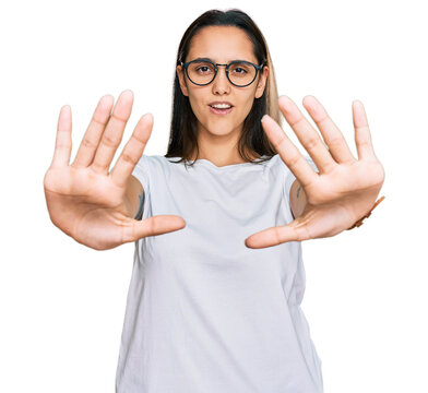 Young hispanic woman wearing casual white t shirt doing stop gesture with hands palms, angry and frustration expression