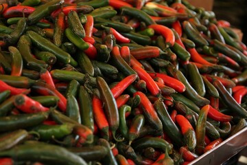 Heap of fresh Serrano peppers on counter at market, closeup