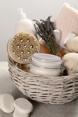Spa gift set of different luxury products in wicker basket on grey table, closeup