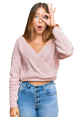 Fototapeta premium Beautiful blonde woman wearing casual winter pink sweater doing ok gesture shocked with surprised face, eye looking through fingers. unbelieving expression.