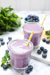 Tasty blueberry smoothie with mint and fresh berries on white marble table, closeup