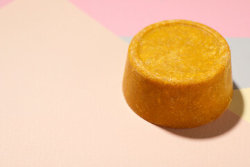 Orange solid shampoo bar on color background, closeup. Space for text