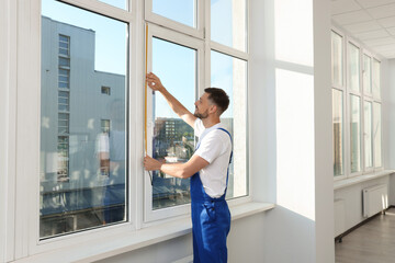 Fototapeta na wymiar Worker measuring plastic window indoors. Installation process
