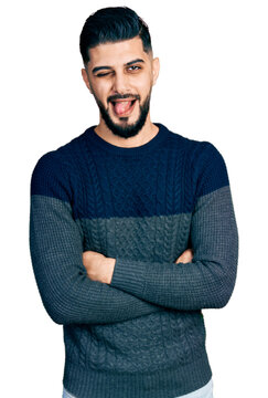 Young arab man with beard with arms crossed gesture sticking tongue out happy with funny expression.