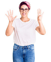 Obraz na płótnie Canvas Young beautiful woman with pink hair wearing casual clothes and glasses showing and pointing up with fingers number nine while smiling confident and happy.