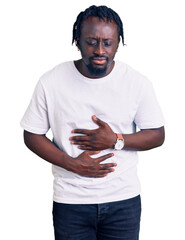 Young african american man with braids wearing casual white tshirt with hand on stomach because indigestion, painful illness feeling unwell. ache concept.