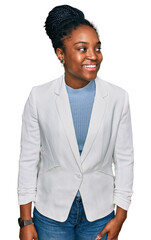 Young african american woman wearing business clothes looking away to side with smile on face, natural expression. laughing confident.