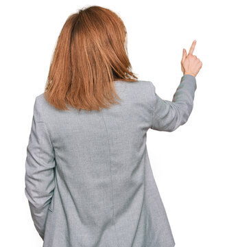 Young caucasian woman wearing business style and glasses posing backwards pointing ahead with finger hand