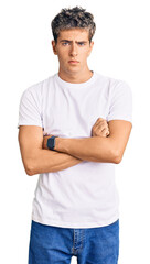 Young handsome man wearing casual white tshirt shaking and freezing for winter cold with sad and shock expression on face