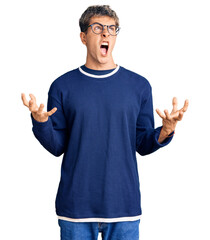 Fototapeta premium Young handsome man wearing casual clothes and glasses crazy and mad shouting and yelling with aggressive expression and arms raised. frustration concept.