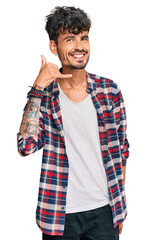 Young hispanic man wearing casual clothes smiling doing phone gesture with hand and fingers like talking on the telephone. communicating concepts.