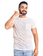Fototapeta premium Young hispanic man wearing casual clothes smiling doing phone gesture with hand and fingers like talking on the telephone. communicating concepts.