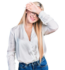 Beautiful blonde woman wearing elegant shirt and glasses covering eyes with arm smiling cheerful and funny. blind concept.