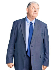 Senior grey-haired man wearing business jacket smiling looking to the side and staring away thinking.