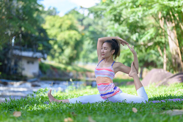 A beautiful young girl doing yoga in the park in the morning., peace and relaxation, woman's happiness
