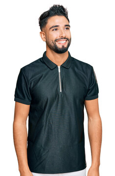 Young man with beard wearing sportswear looking away to side with smile on face, natural expression. laughing confident.