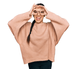 Young hispanic girl wearing casual clothes and glasses doing ok gesture like binoculars sticking tongue out, eyes looking through fingers. crazy expression.