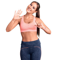 Young beautiful hispanic woman wearing sportswear showing and pointing up with fingers number seven while smiling confident and happy.
