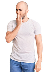 Young handsome man wearing casual t shirt bored yawning tired covering mouth with hand. restless and sleepiness.