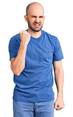 Obraz premium Young handsome man wearing casual t shirt angry and mad raising fist frustrated and furious while shouting with anger. rage and aggressive concept.