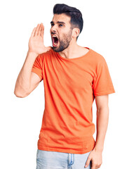 Young handsome man with beard wearing casual t-shirt shouting and screaming loud to side with hand on mouth. communication concept.