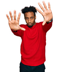 Young african american man with beard wearing casual winter sweater doing frame using hands palms...
