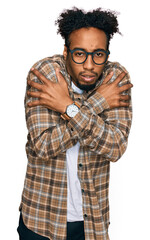 Young african american man with beard wearing casual clothes and glasses shaking and freezing for winter cold with sad and shock expression on face
