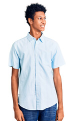 Young african american man wearing casual clothes looking away to side with smile on face, natural expression. laughing confident.