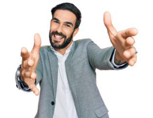 Young hispanic man wearing business clothes looking at the camera smiling with open arms for hug. cheerful expression embracing happiness.