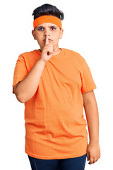 Little boy kid wearing sportswear asking to be quiet with finger on lips. silence and secret concept.