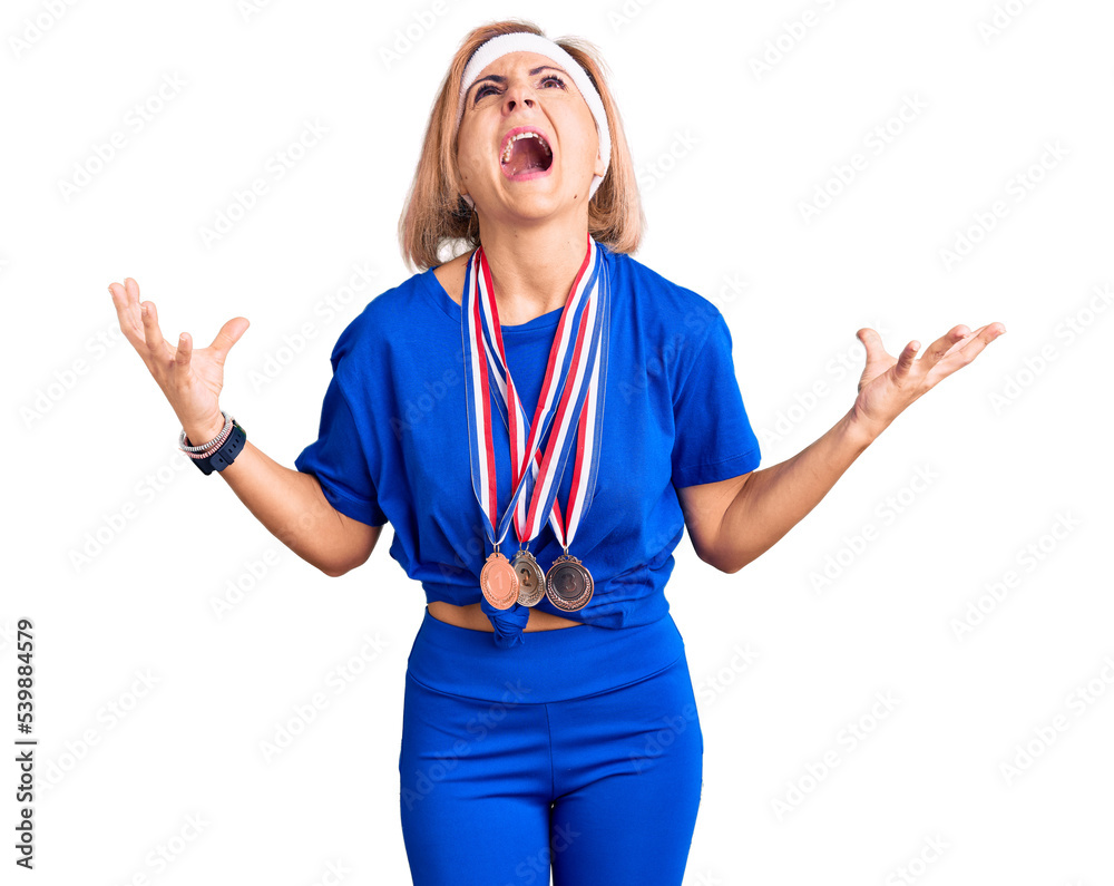 Sticker Young blonde woman wearing winner medals crazy and mad shouting and yelling with aggressive expression and arms raised. frustration concept.