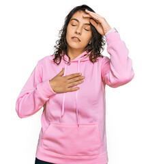 Young hispanic woman wearing casual sweatshirt touching forehead for illness and fever, flu and cold, virus sick