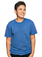 Teenager hispanic boy wearing casual clothes looking away to side with smile on face, natural expression. laughing confident.