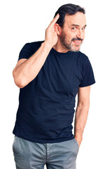 Middle age handsome man wearing casual t-shirt smiling with hand over ear listening an hearing to...