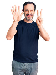 Middle age handsome man wearing casual t-shirt showing and pointing up with fingers number seven while smiling confident and happy.