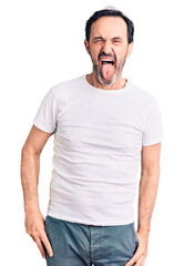 Obraz premium Middle age handsome man wearing casual t-shirt sticking tongue out happy with funny expression. emotion concept.
