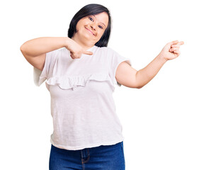 Fototapeta na wymiar Brunette woman with down syndrome wearing casual white tshirt smiling and looking at the camera pointing with two hands and fingers to the side.