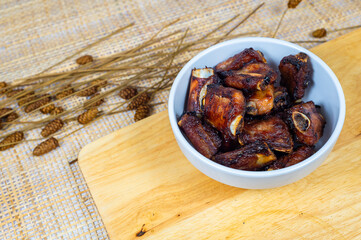 Top view of grilled pork ribs in a bowl on a wooden board, Obesity causes, Cancer causes, Unhealthy food.