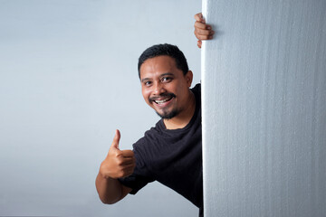 happy man with thumb up peeking behind wall