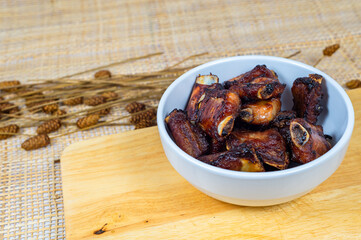Top view of grilled pork ribs in a bowl on a wooden board, Obesity causes, Cancer causes, Unhealthy food.