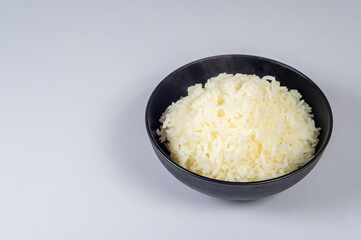 Top view of Rice in a black bowl on a white background, Copy space for text.