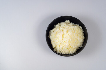 Top view of Rice in a black bowl on a white background, Copy space for text.